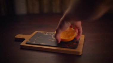 Yetenekli bir el taze, sulu bir portakalı yumuşak ve mermer bir kesme tahtasının üzerine nazikçe sıkar. Yemek tasarımı için ideal.