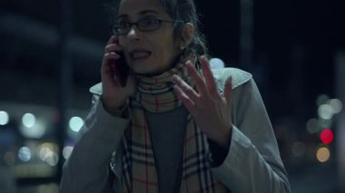 Canlı bir gece hayatı ortamında telefon görüşmesi yapan bir kadın sıkıntı yaşıyor gibi görünüyor.