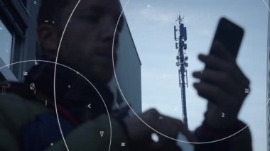 Birisi akıllı telefonunu baz istasyonunun yanında kullanıyor. Çevremizdeki gelişen teknolojiyi ve bağlantıyı sembolize ediyor.