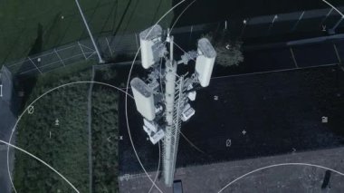 Çarpıcı bir drone atışı geniş bir hücresel kuleye ve yemyeşil bir ortamda karmaşık sinyal desenlerine sahiptir.