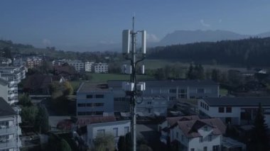 Bir telekomünikasyon kulesi, yerleşim binaları ve çevresindeki dağların arasında uzun ve belirgin duruyor.