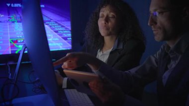 İki finans uzmanı ekranlardaki mali verileri inceleyerek pazar eğilimleri ve temel analitik kavrayışları tartıştılar