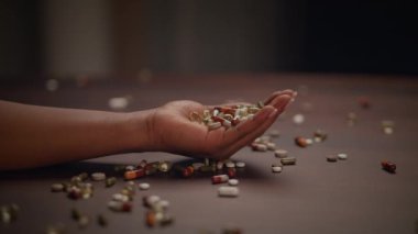 Ahşap bir yüzeye dikkatlice yerleştirilmiş renkli haplardan oluşan bir el görüntüsü.