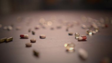 Masanın yüzeyine dağılmış çeşitli renkli hapların detaylı ve yakın görüntüsü.