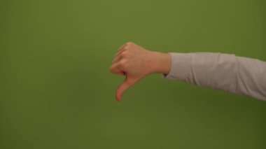 Bir el, canlı ve göz alıcı yeşil bir arkaplan karşısında baş parmaklarını aşağı hareket ettiriyor.