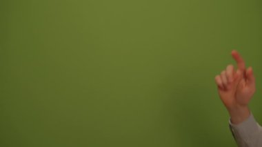 Hareketli yeşil bir duvarın önünde, sunumlar için ideal bir el hareketinin yakın çekimi.