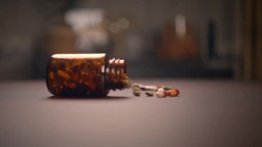 İlaç şişesinin üzerine devrilmiş ve kapsülleri yakınlardaki düz bir yüzeye saçılmış yakın çekim görüntüsü.