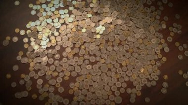 Ahşap bir yüzeye saçılmış çeşitli madeni paraların yakın plan görüntüsü, farklı boyut ve renkler sergiliyor..