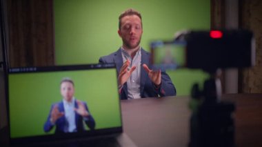 Bir adam canlı, yeşil bir ekranın önünde duruyor ve oldukça profesyonel bir video kayıt cihazı sergiliyor.
