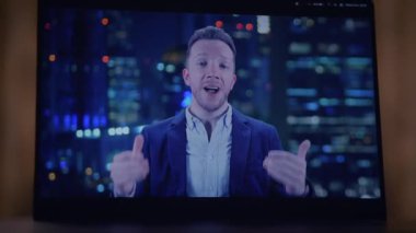 Çok yetenekli bir profesyonel konuşmacı, izleyicileri canlı bir şehir arkaplanına karşı bir ekrandan cezbediyor ve onları kendine çekiyor.