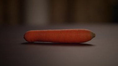 Taze ve çıtır çıtır bir havuç, canlı rengini ve eşsiz dokusunu canlı bir şekilde gözler önüne seren koyu bir yüzeyde duruyor.