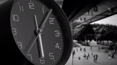 Çarpıcı bir siyah beyaz görüntü hayat dolu hareketli ve dinamik bir şehir zeminine karşı bir saat sergiliyor.