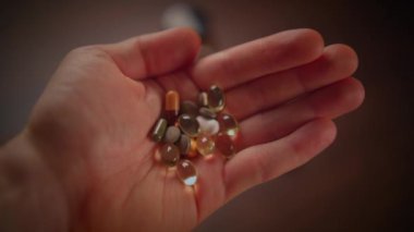 Canlı, renkli besin takviyeleri ve vitaminlerden oluşan çeşitli seçimleri kavrayan bir elin yakın plan görüntüsü.