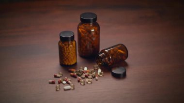 Bir dizi bitkisel destek kapsülü şişelerinden kırsal ahşap masa yüzeyine döküldü.