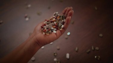 Bir el, sağlığını ve sağlığını simgeleyen çeşitli canlı hapların rengarenk bir karışımını sıkıca tutar.