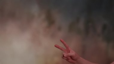 Güneşli günbatımında ya da gündoğumunda izole edilmiş bir kadın eli dışarıda barış ya da zafer jesti gösteriyor. Yakından, iki parmağı havada bir kadının 4K video görüntüsü. Yüksek