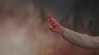 Odaklanmış bir fotoğraf, zengin desenli ve renkli bir arkaplana karşı farklı bir el hareketi yapan bir eli gösteriyor.