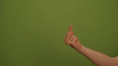Bir el, koyu yeşil bir zemine karşı kışkırtıcı bir hareket sergiliyor ve görsel etki yaratıyor.
