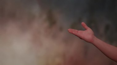 Dumanlı, soyut bir arka plana karşı bir el yakalayan yakın plan görüntüsü, derinlik ve keşfi sembolize eder.