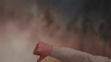 Bir el, yumuşak odaklı, bulanık arka plana karşı baş parmağıyla bir jest yaparken görülüyor.