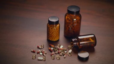 Farklı haplar, kapsüller ve destek şişeleri kırsal bir ahşap masa üzerinde titizlikle düzenlenmiştir.