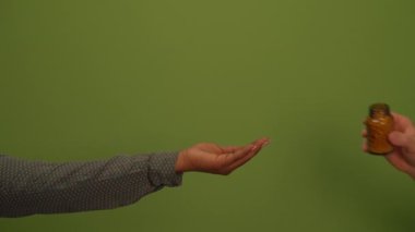 Yakından çekilmiş bir resim zarif bir şekilde uzanan bir eli canlı, yemyeşil bir arkaplanda gösteriyor.