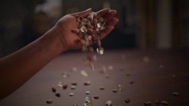 Bir el nazikçe kırsal bir ahşap masada etrafa saçılmış taşlarla çevrili renkli taşlardan oluşan hoş bir çeşitlilik tutar.