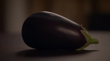 Canlı bir patlıcan güzel bir şekilde ahşap bir masanın üzerinde duruyor, zengin rengini ve pürüzsüz dokusunu gözler önüne seriyor.