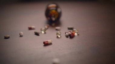 Rengarenk ilaç kapsülleri ahşap bir masanın üzerinde zarif bir şekilde duran parlak bir kürenin etrafına saçıldı.