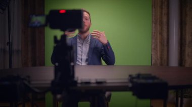 Uzman bir konuşmacı, video üretimi için profesyonel bir yeşil ekran ayarı kullanarak izleyiciyle bağlantı kurar