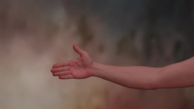 Bir insan elinin yakın çekimi, güzel bir bulanık arka plana karşı davetkar bir jest yapıyor.