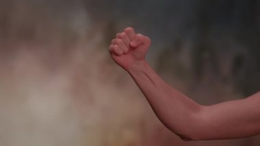 Kalkmış yumruğun güçlü bir görüntüsü gücü ve dayanışmayı simgeliyor bulanık, renkli bir arkaplanda.