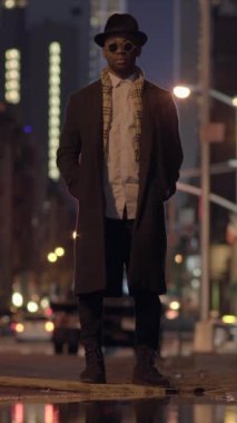 Şık bir şahsiyet, kentin hareketli caddesinde kendine güvenle duruyor, modern şehir modasını gözler önüne seriyor.