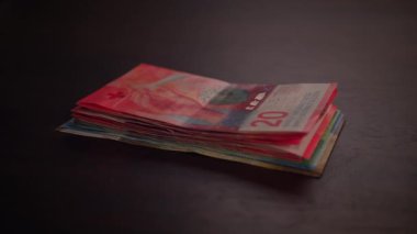 Koyu arkaplandaki canlı para birimi notlarının yakın görüntüsü, renklerini ve detaylarını gösteriyor