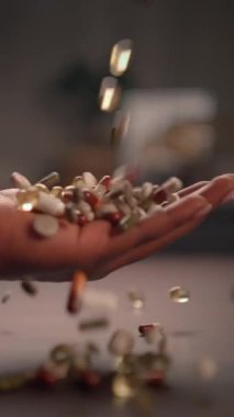 Çeşitli vitaminler ve takviyeler salan bir el, genel sağlık ve sağlığı sembolize eder.