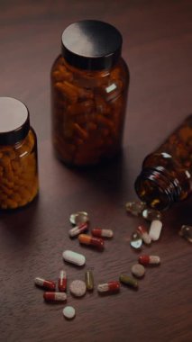 Birçok ilacın yanı sıra çeşitli haplar kırsal bir ahşap masaya dikkatsizce saçılmıştır.