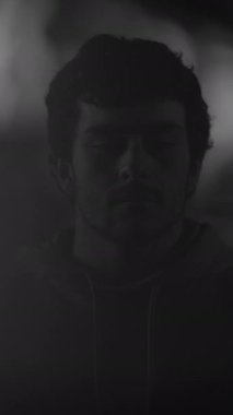 Gözleri kapalı genç bir adam, derin düşüncelere dalmış, çarpıcı siyah beyaz bir fotoğrafa yakalandı.