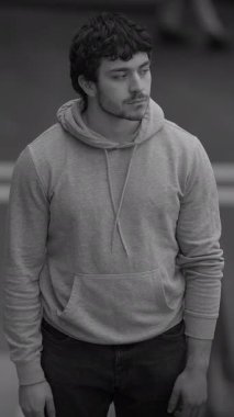 Rahat bir ortamda, gri kapüşonlu düşünceli genç bir adam derin düşüncelere dalmış ve derin düşüncelere dalmış.