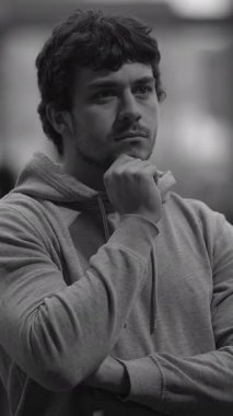 Derin düşüncelere dalmış genç bir adam, güzel bir şekilde siyah-beyaza bürünmüş, içyüzünü gösteriyor ve odaklanıyor.