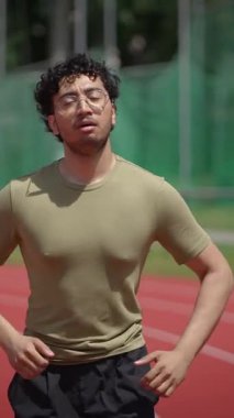 Genç bir adam mutlu bir şekilde spor pistinde koşuyor, tam olarak vücut bulmuş spor ve sağlık hareket ve hareket halinde.