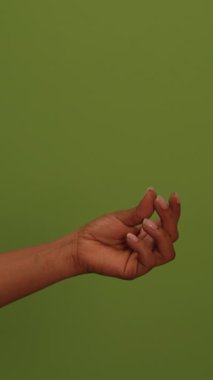 Canlı yeşil bir arkaplan karşısında güzel poz veren el hareketi, gerçek zarafet ve basitliği temsil eder.
