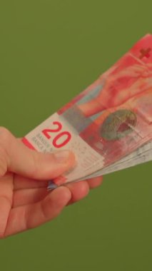 20 franklık İsviçre banknotunu sıkıca kavrayan bir elin detaylı yakın plan çekimi.