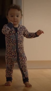 Renkli desenli pijama giymiş neşeli bir çocuk bir adım atar ve saf çocukluk masumiyetini gözler önüne serer.