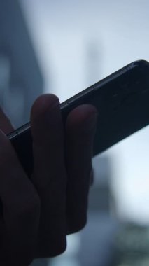Bu görüntü, şehir zemininin bulanık olmasına rağmen akıllı telefonu sıkıca kavrayan bir elin detaylı görüntüsünü yakalar.