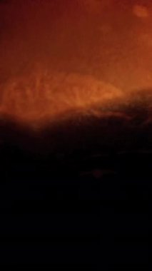 Çarpıcı bir görüntü, parlak, turuncu tonlarda koyu bir arkaplanda dalgalanan alev desenleri gösteriyor..