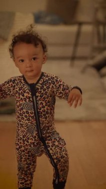 Neşeli bir bebek, canlı bir tulum giyiyor, neşeli ve eğlenceli bir çevrede keşfe çıkıyor.