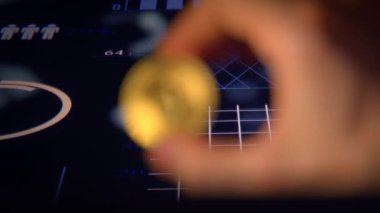 Finansal grafikleri olan ve kripto para yatırımını sembolize eden bir Bitcoin 'i tutan bir el..