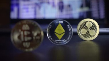Görüntü, Bitcoin, Ethereum ve Ripple paralarının popüler kripto para birimlerini sembolize eden yakın çekimini gösteriyor.
