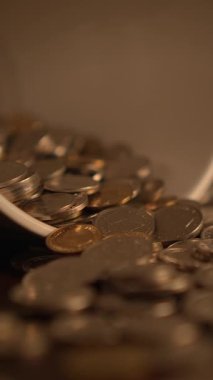 Zenginlik, para ve finans temalarını vurgulayarak, bir kaseden dökülen sikkeleri gösteren yakın plan bir görünüm