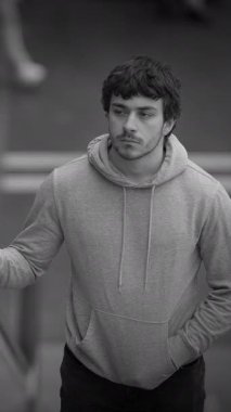 Gri kapüşonlu, düşünceli genç bir adam dışarıda dikiliyor, derin derin düşünüyor ve dalgın dalgın dalgın dalgın dalgın dalgın dalgın dalgın dalgın dalgın bakıyor.